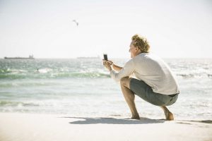 Un hombre toma una fotografía con la cámara del móvil en la playa